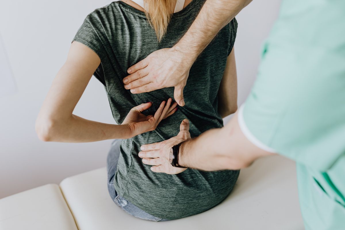 Physical therapist assessing a patient’s upper back during a clinic visit